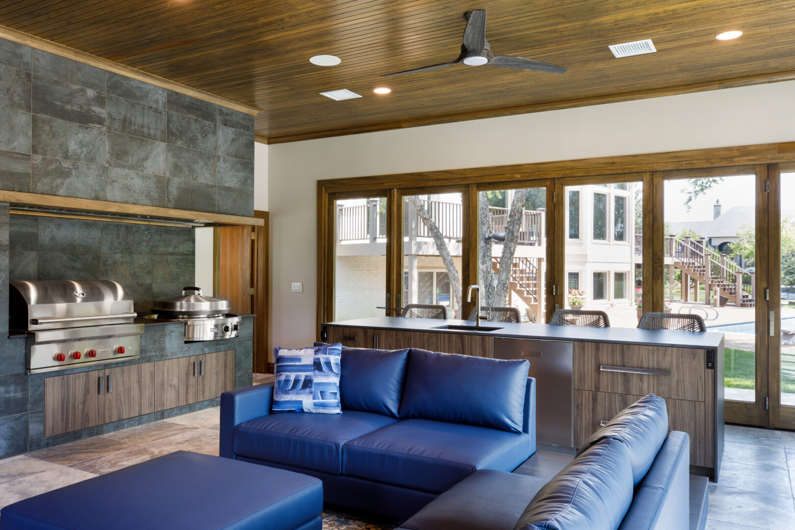 Contemporary living room featuring large windows, blue sofa, and wooden accents in Wichita, Kansas.