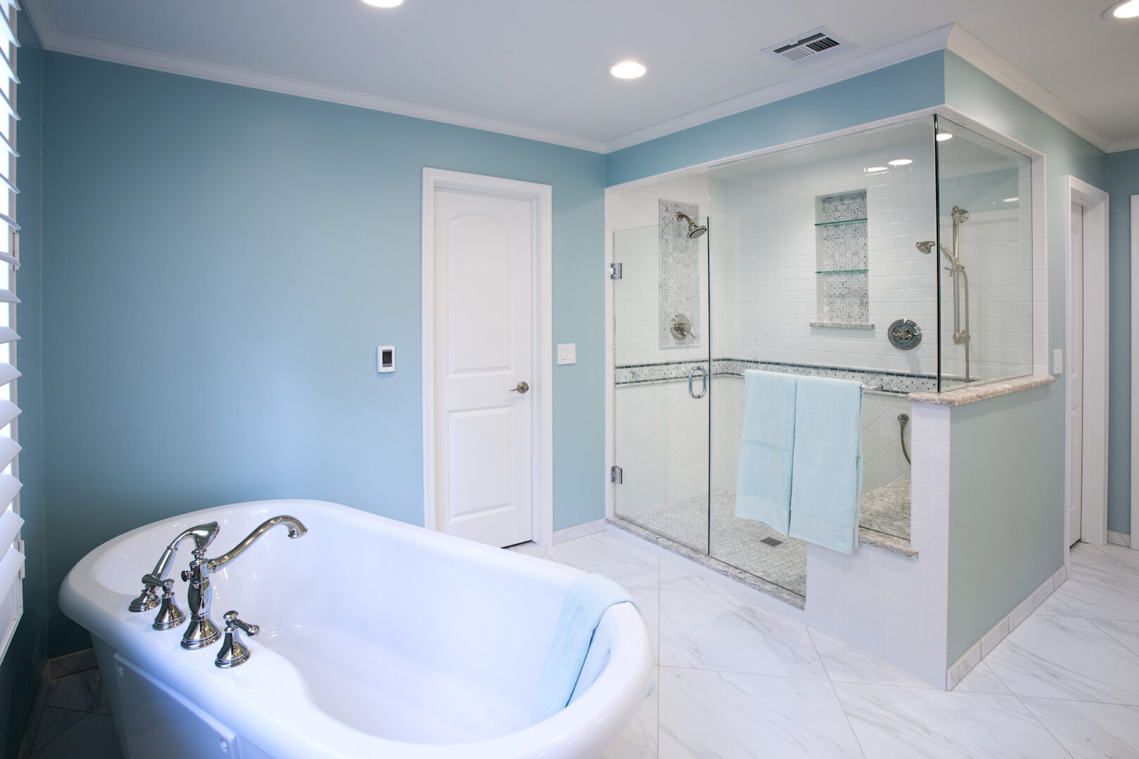 Bathroom with walk-in shower and bathtub, featuring light blue walls and modern fixtures in Wichita,.