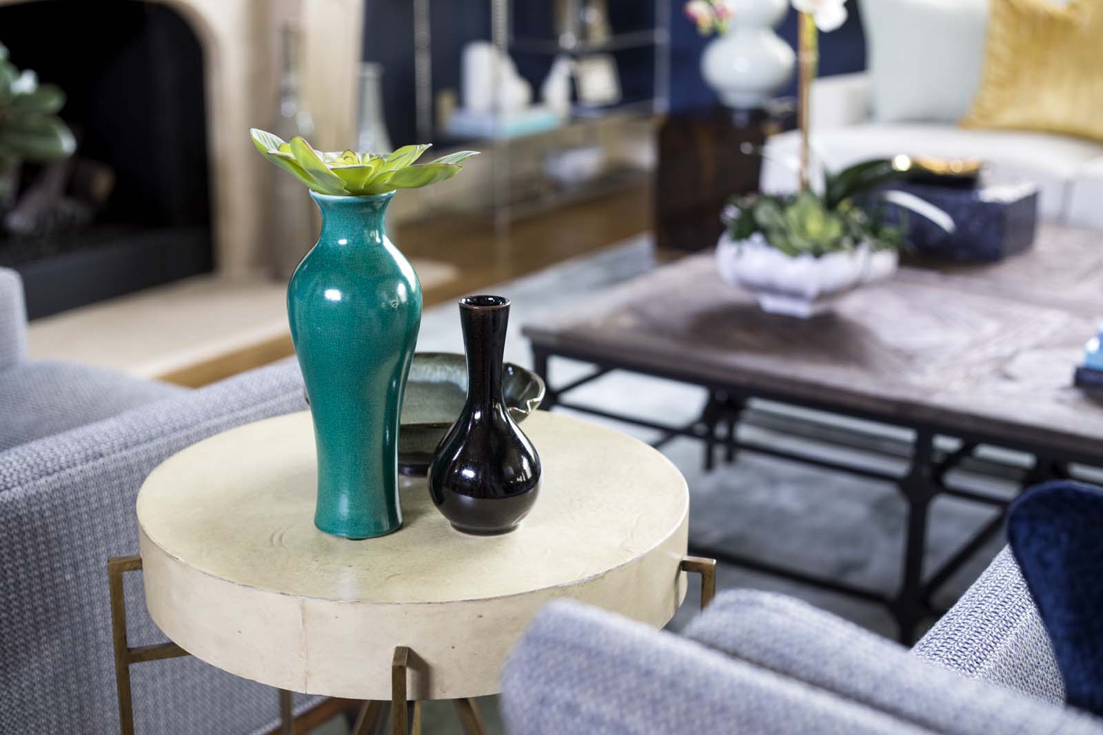 Contemporary living room featuring a round table with colorful vases and cozy seating arrangements.