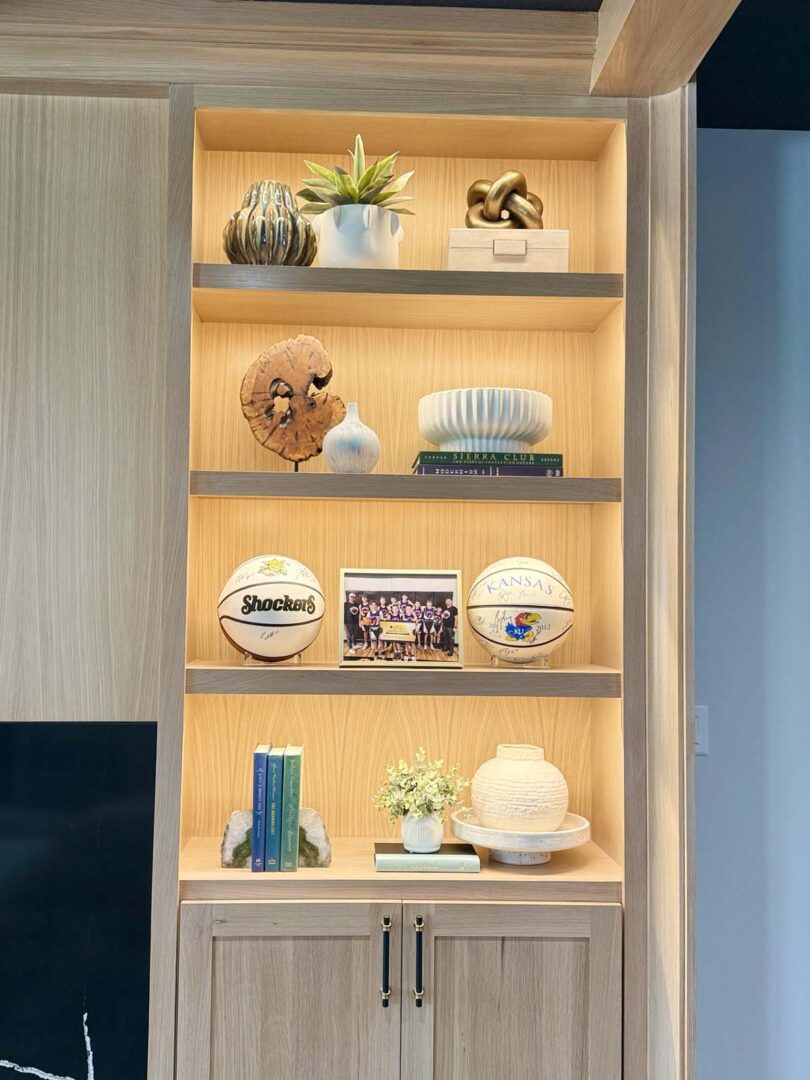 Built-in wooden shelf displaying decorative objects, books, and plants in a contemporary interior.