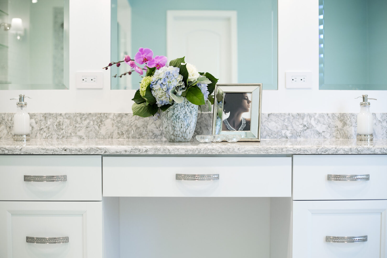 Bathroom vanity with floral arrangement and framed photo in a modern space.