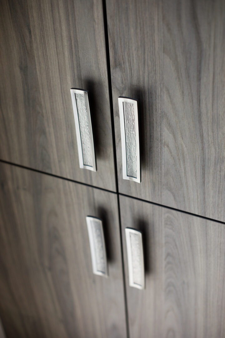 Wooden cabinet with silver handles in a contemporary interior setting.