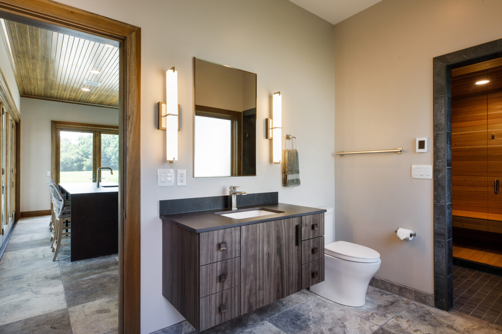 Bright bathroom featuring a contemporary wooden vanity, wall-mounted mirror, and modern lighting fix.