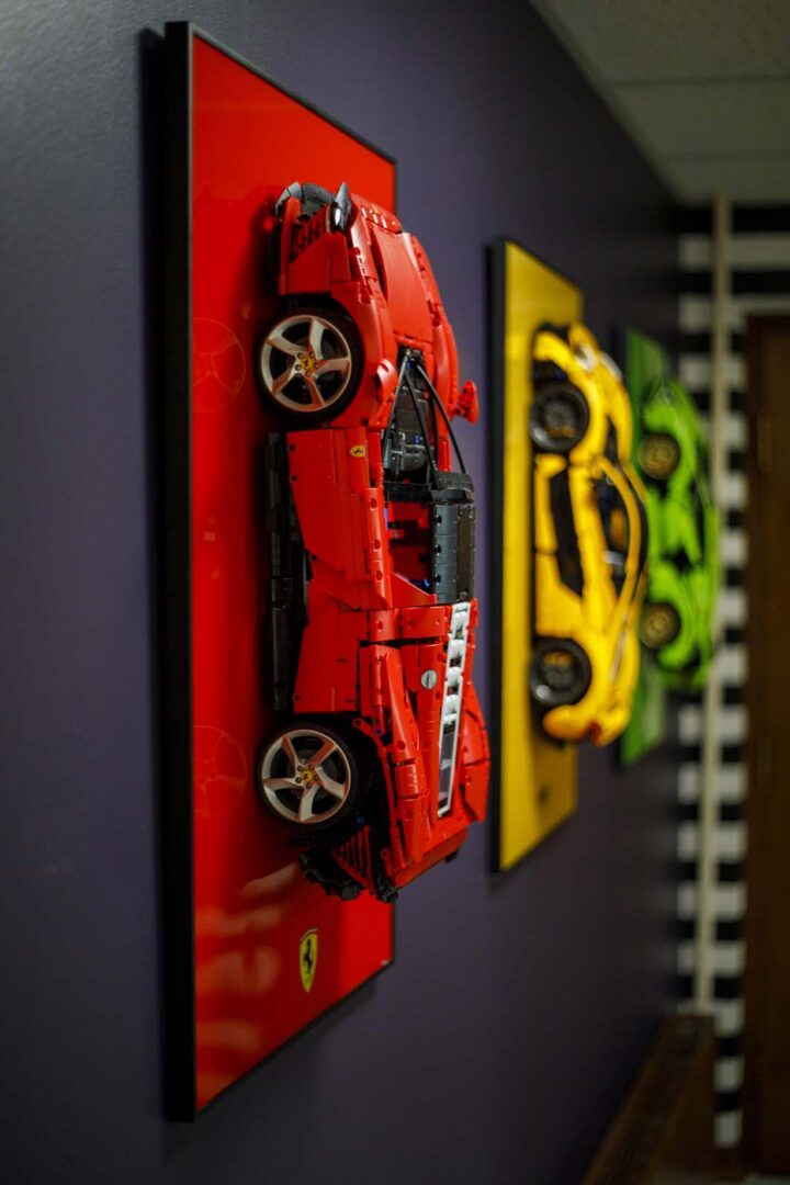 Red Ferrari wall art with yellow and green sports cars in the background.
