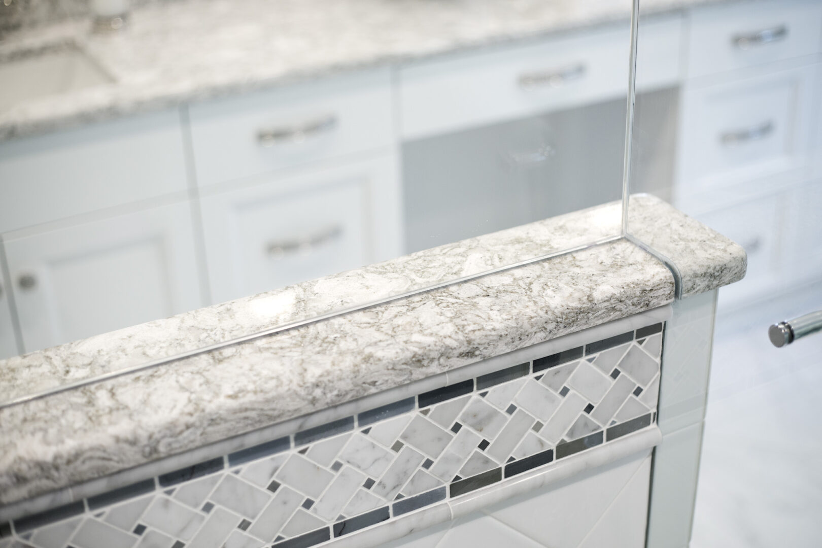 Modern kitchen countertop with granite surface, glass partition, and decorative tile backsplash.