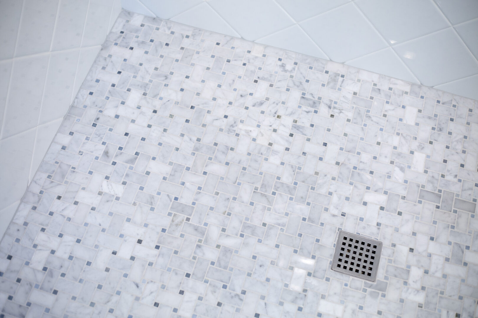 Bathroom floor tile with mosaic pattern and drain.
