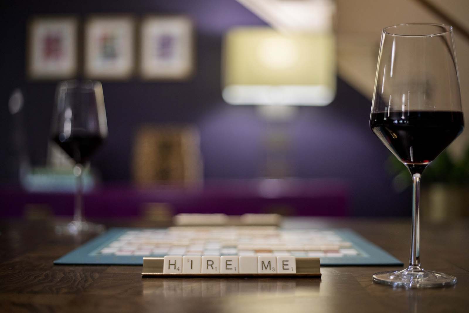 Elegant wine glasses and Scrabble game on a wooden table in a cozy, modern interior setting.