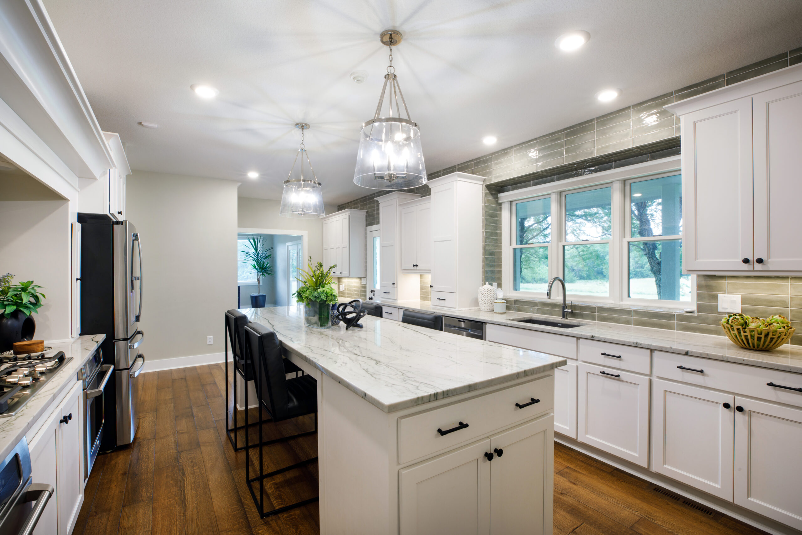 Bright modern kitchen featuring white cabinets, large island, and pendant lights in Wichita, Kansas.