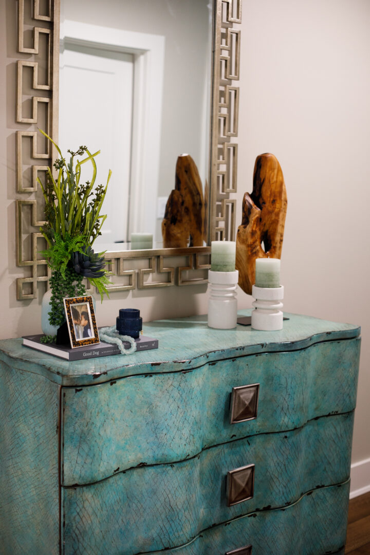 Elegant turquoise dresser with decorative accessories and mirror in interior design setting.
