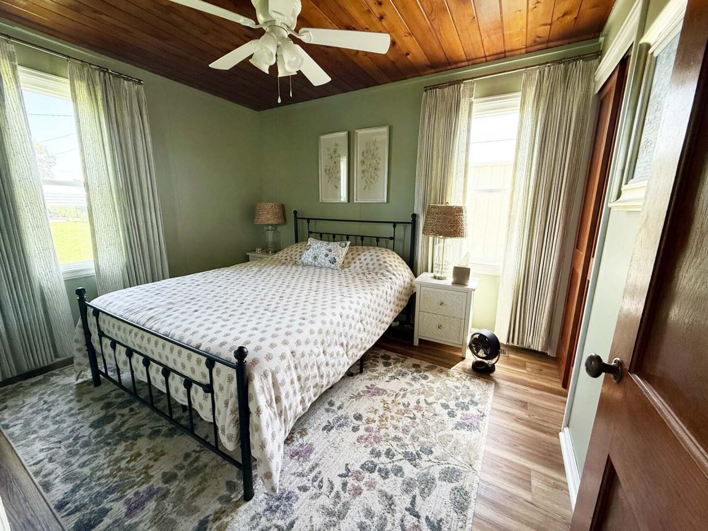 Bedroom with green walls, wooden ceiling, and large windows with white curtains in Wichita, Kansas.