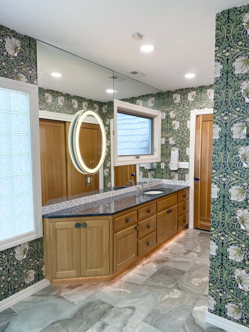Elegant bathroom with floral wallpaper, wooden vanity, and modern mirror lighting.