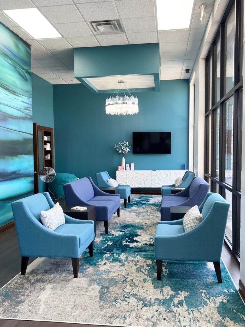 Contemporary lounge with blue chairs, teal walls, and large windows in Wichita, Kansas.