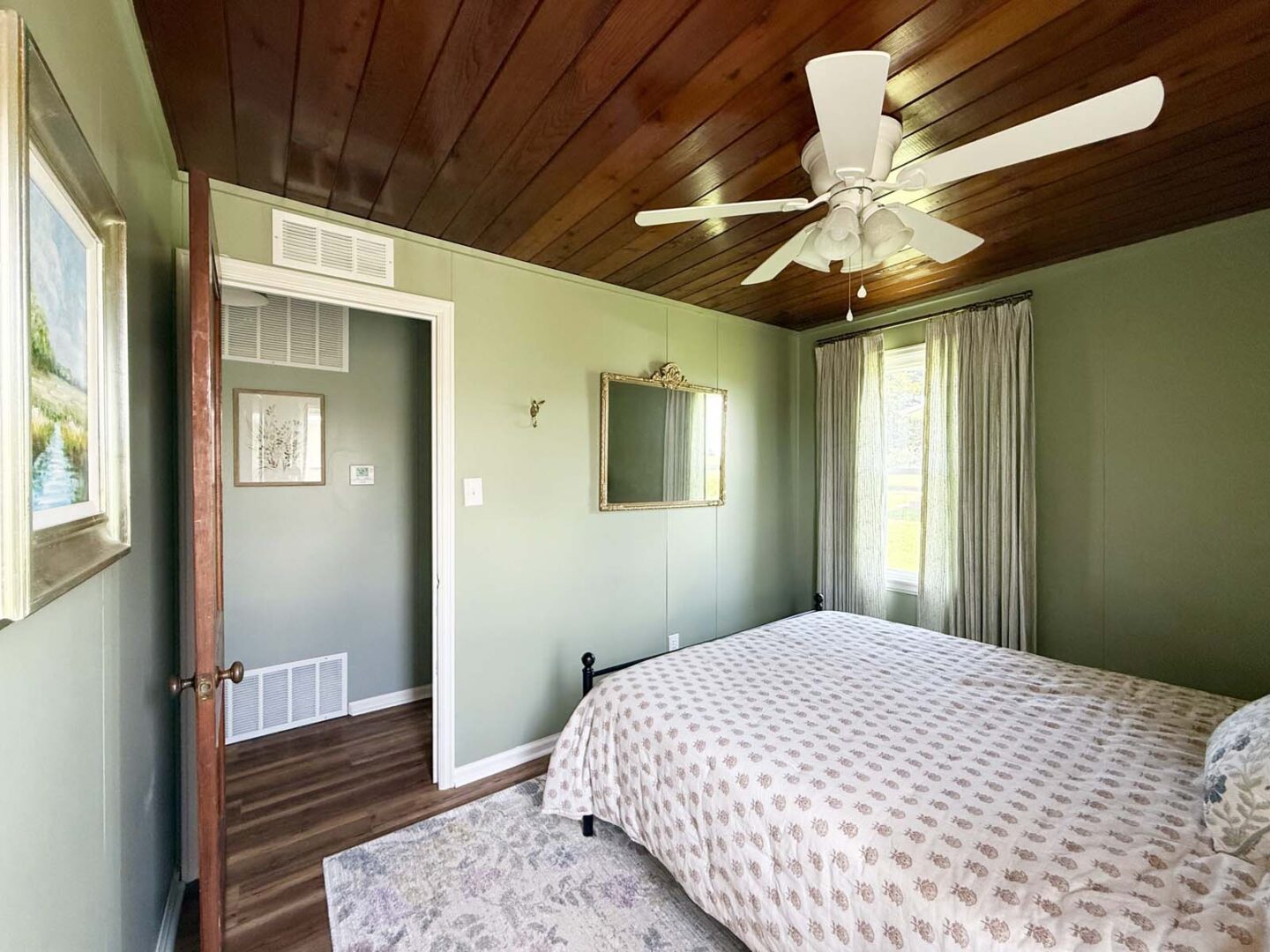 Interior bedroom with green walls, wooden ceiling, ceiling fan, and natural light from windows.