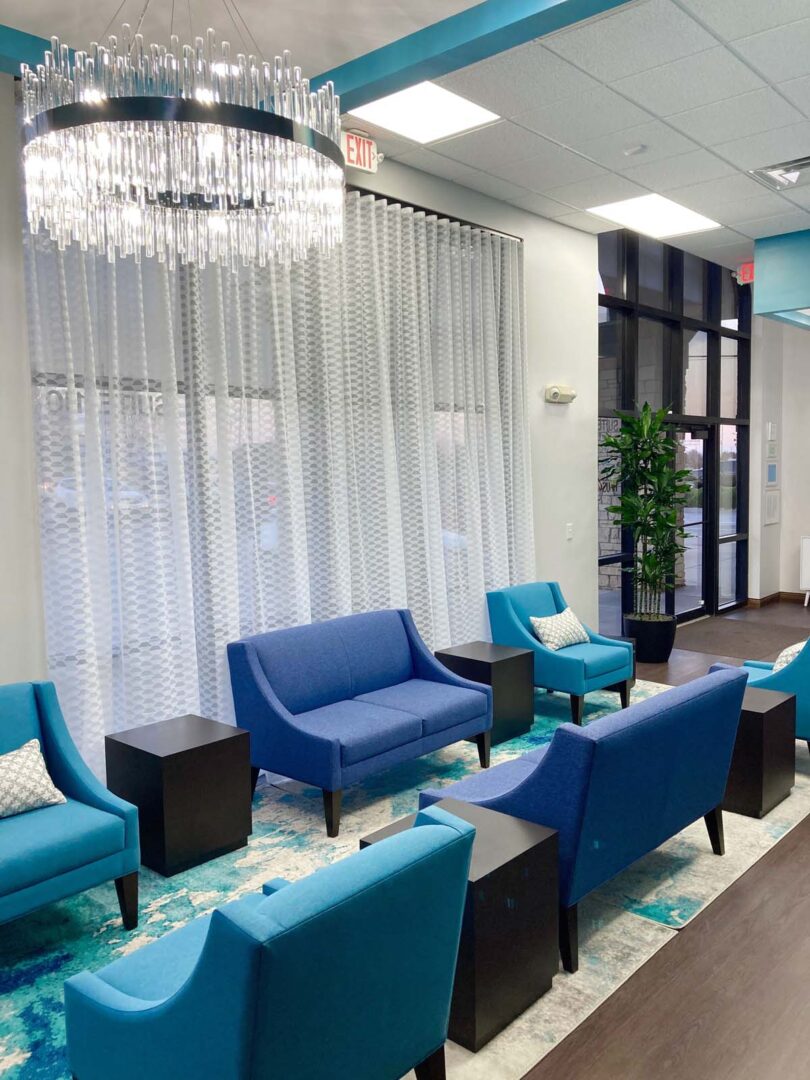 Bright, stylish waiting area featuring blue sofas, armchairs, and decorative curtains.
