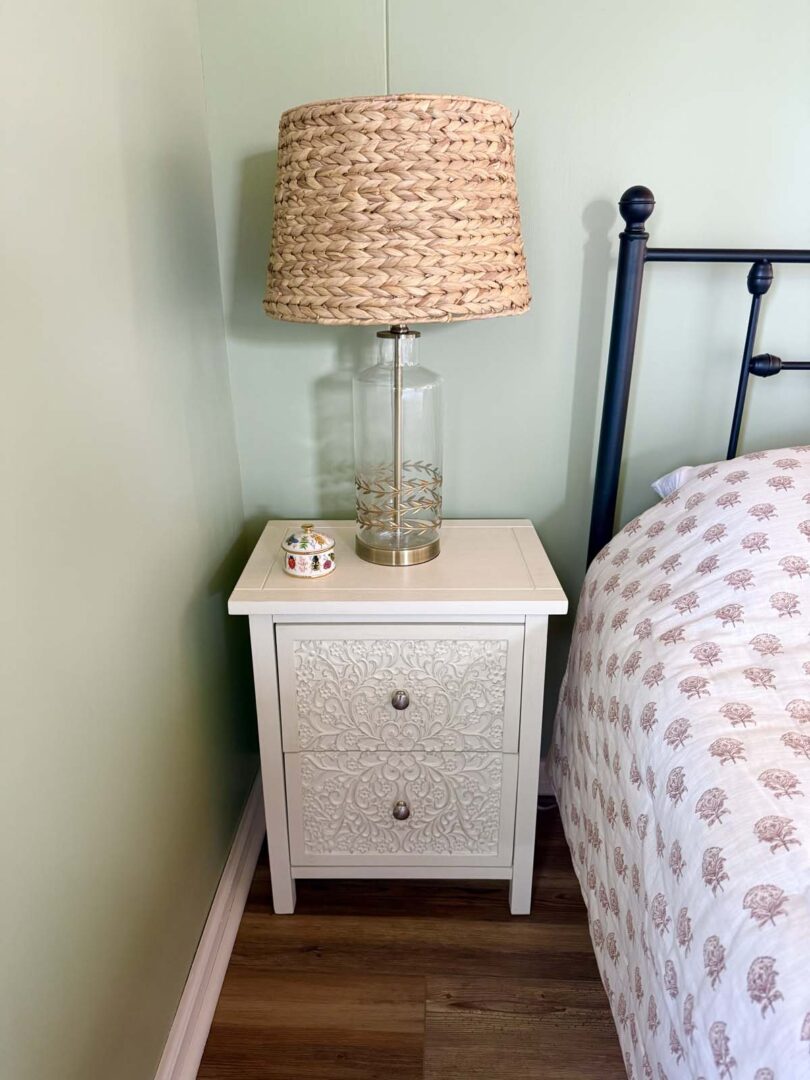 Nightstand with woven lamp in a bedroom setting.