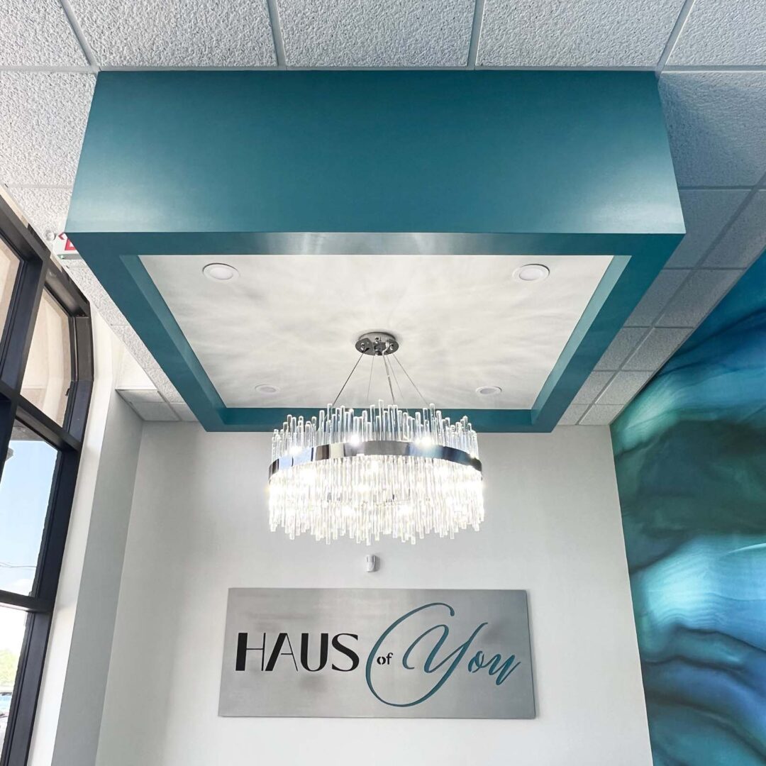 Modern interior ceiling with a decorative teal box and a crystal chandelier.