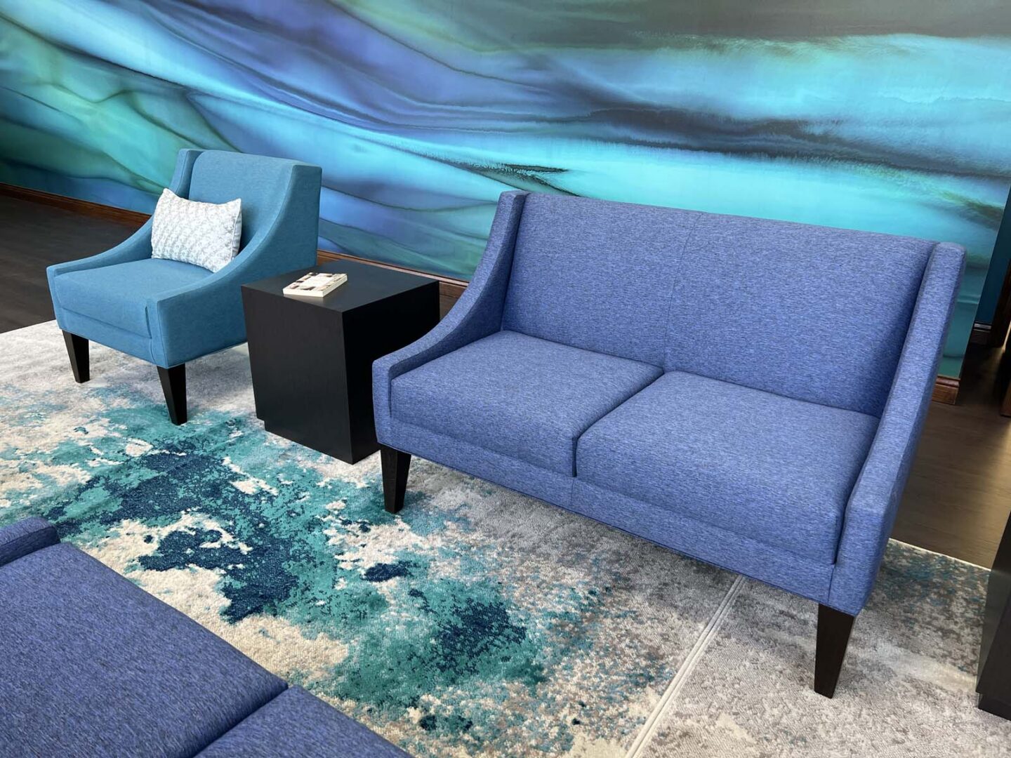Blue sofa and armchair with decorative pillow in contemporary interior design setting.