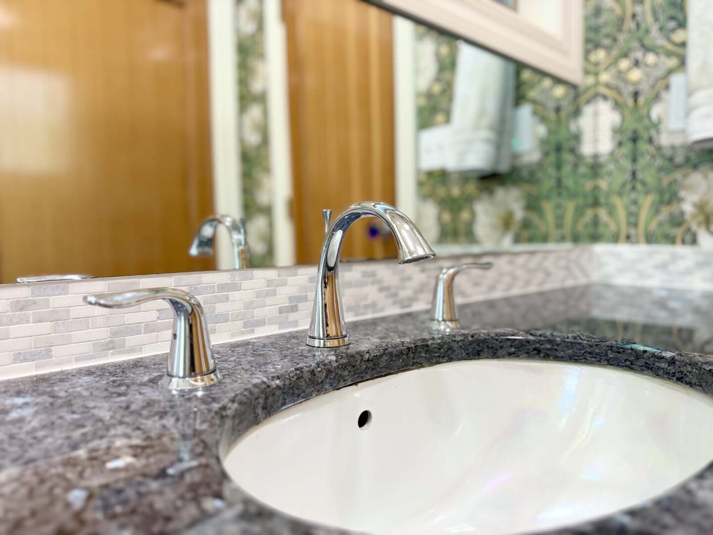 Modern bathroom sink with chrome fixtures and mosaic tile backsplash in interior design.