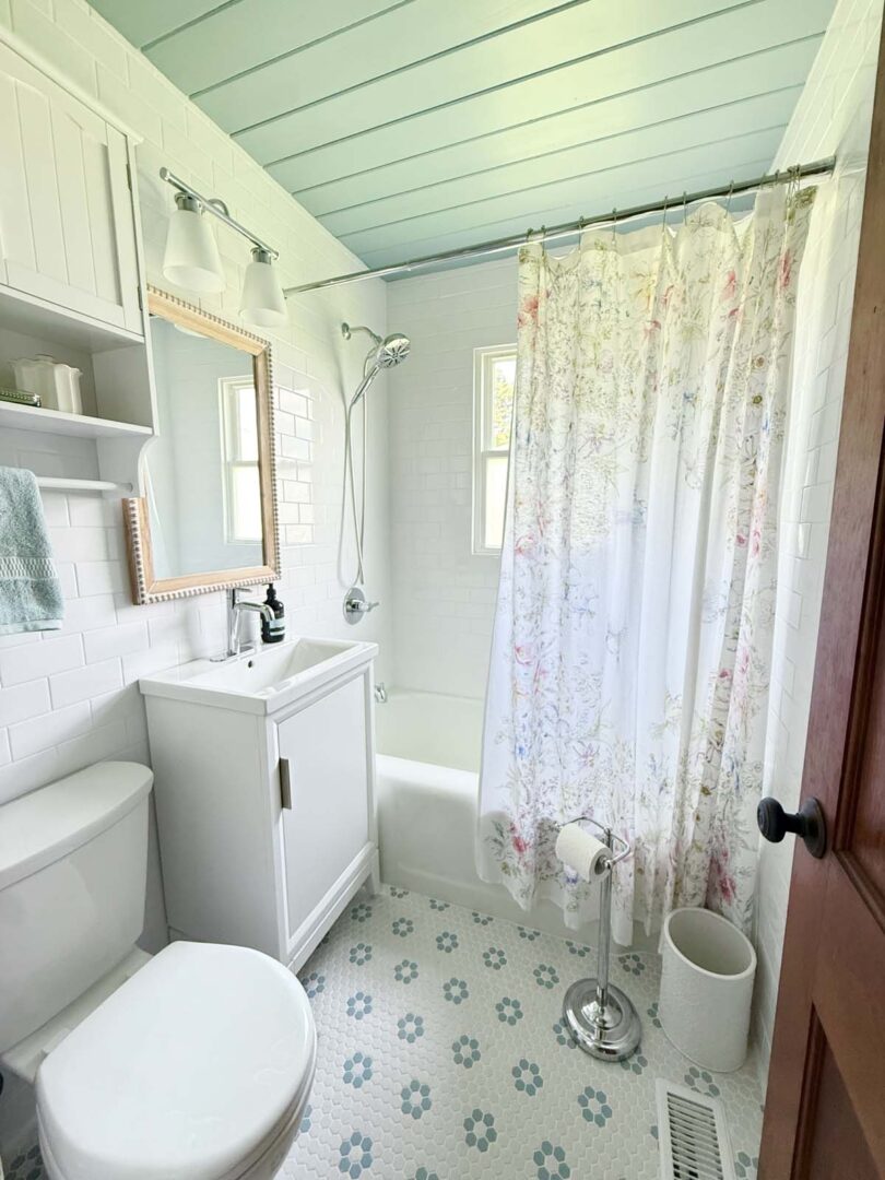 Small bathroom featuring a white vanity, floral shower curtain, and vintage-style decor.