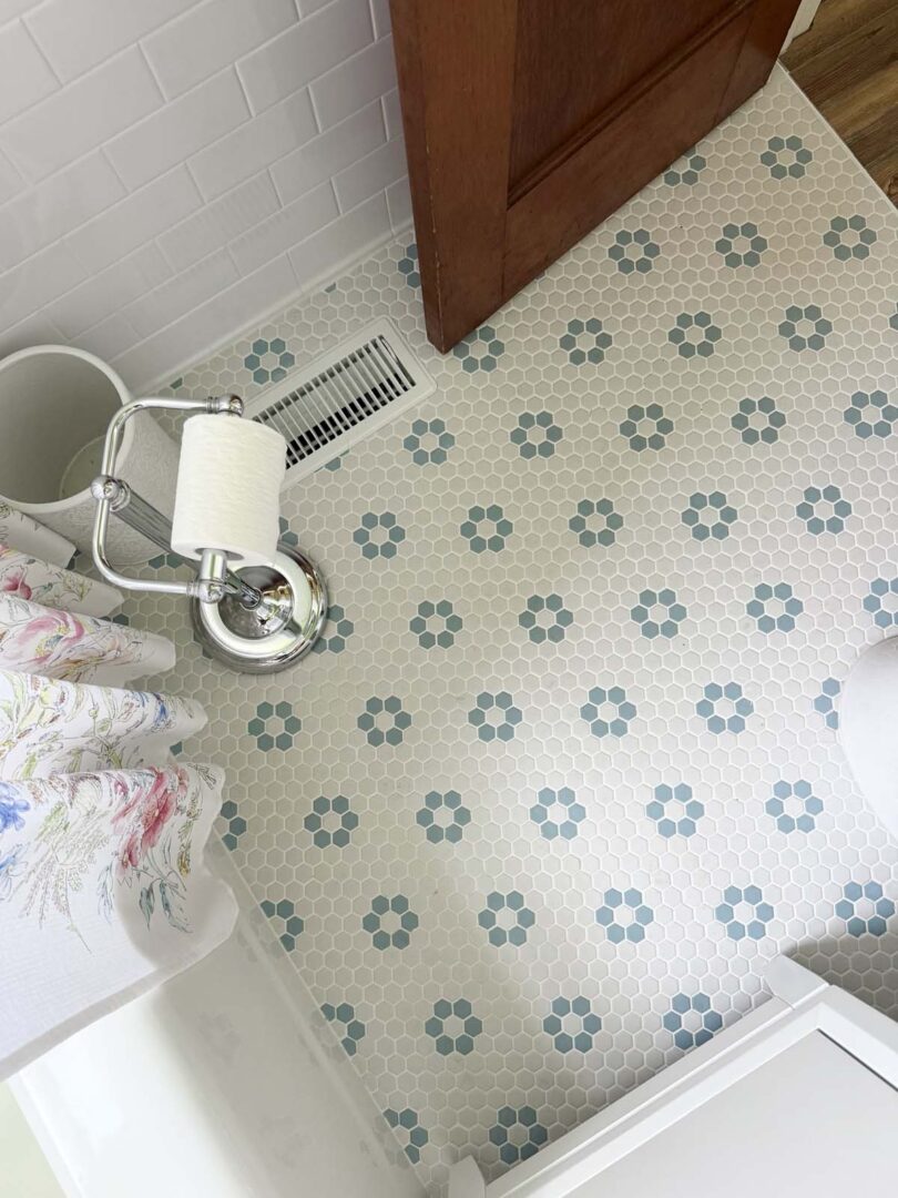 Bright bathroom corner featuring vintage-style floral patterned floor tiles in blue and white.