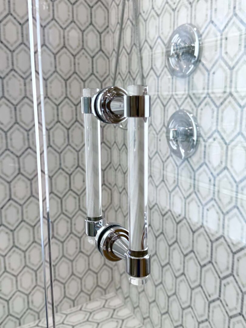 Chrome shower grab bar mounted on hexagonal tile wall for safety and support.