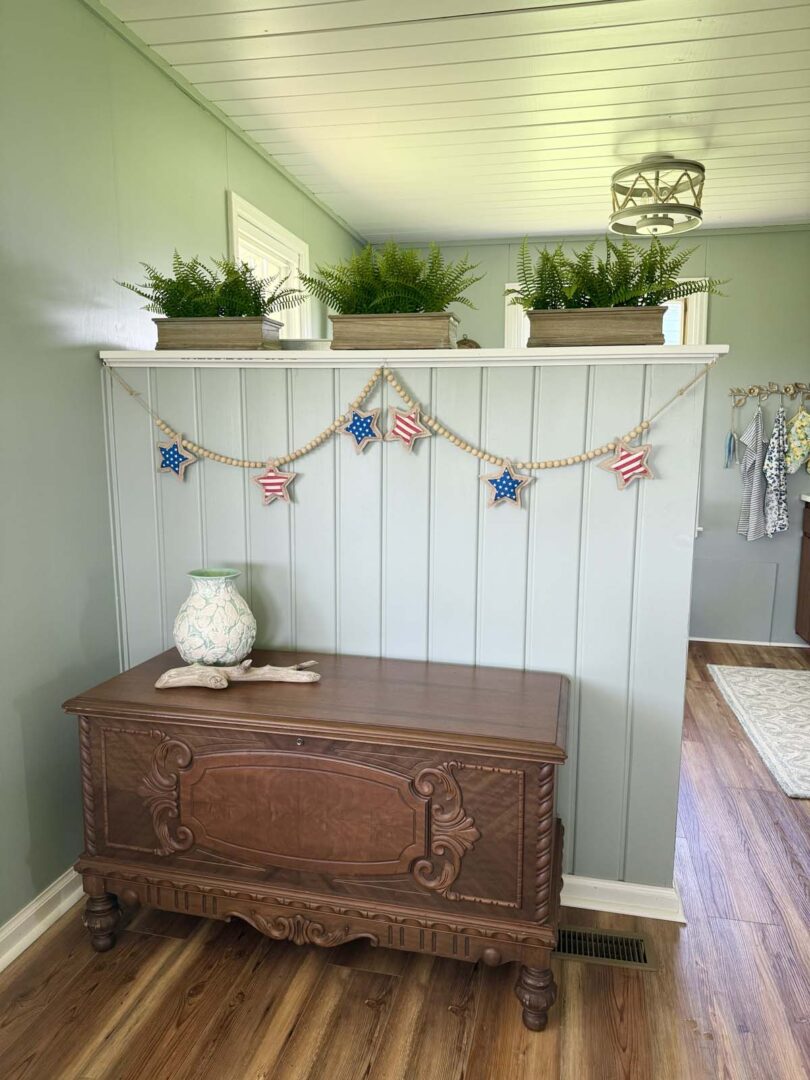 Inviting entry area featuring a wooden console, patriotic garland, and potted greenery.