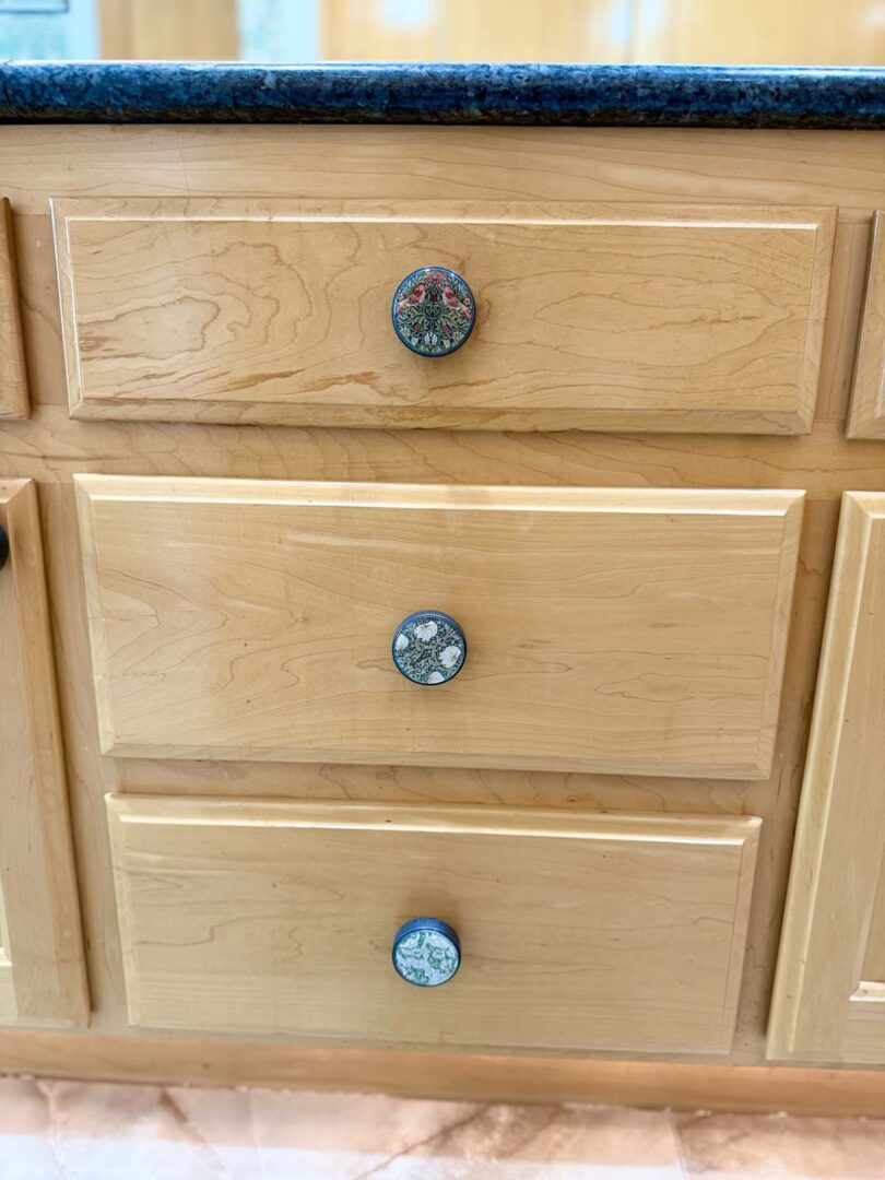 Wooden kitchen drawers with decorative knobs in a light finish.