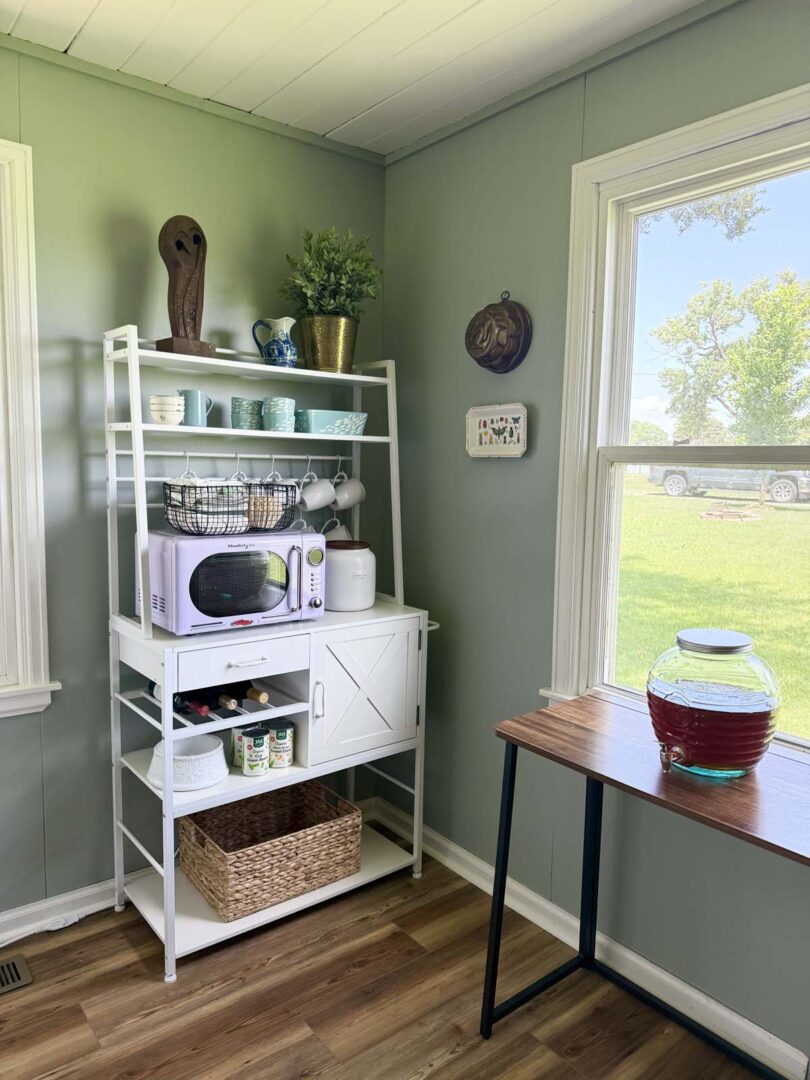 Bright corner with green walls, white shelving, and a wooden table with a glass jar.