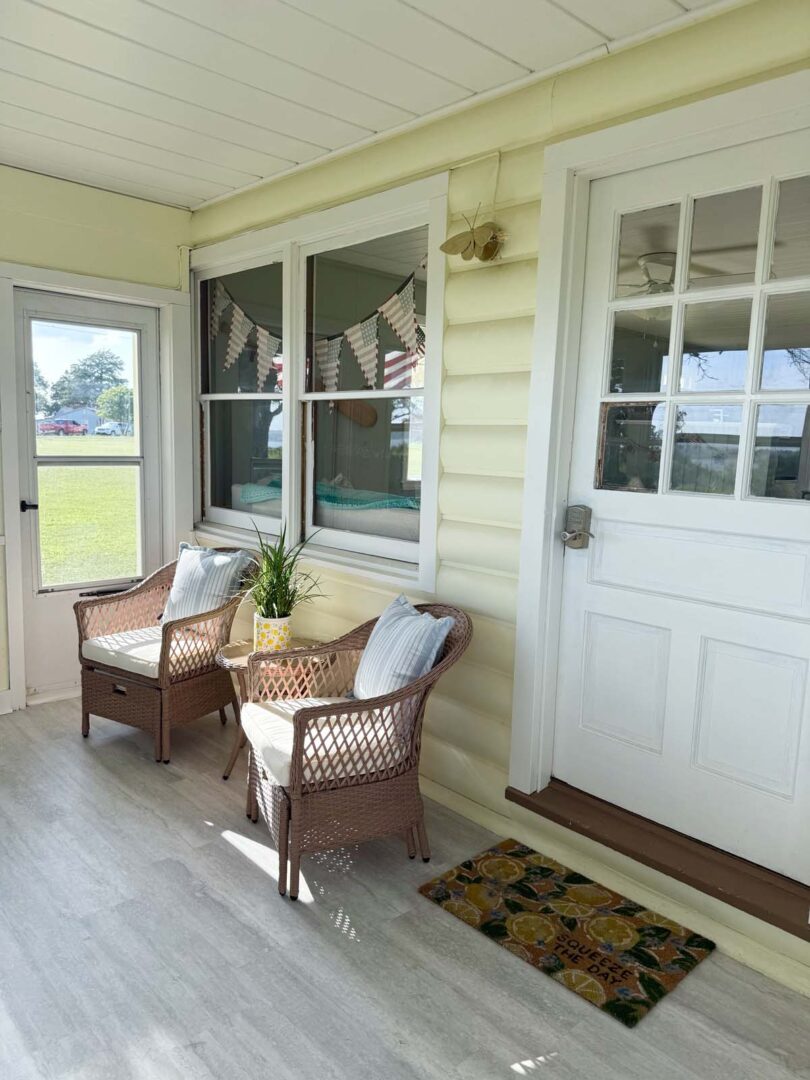 Bright sunroom with wicker chairs, potted plant, and decorative bunting.