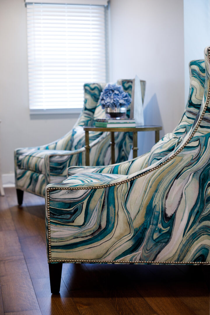 Pair of marbled-pattern armchairs with nailhead trim in a sunlit living room.